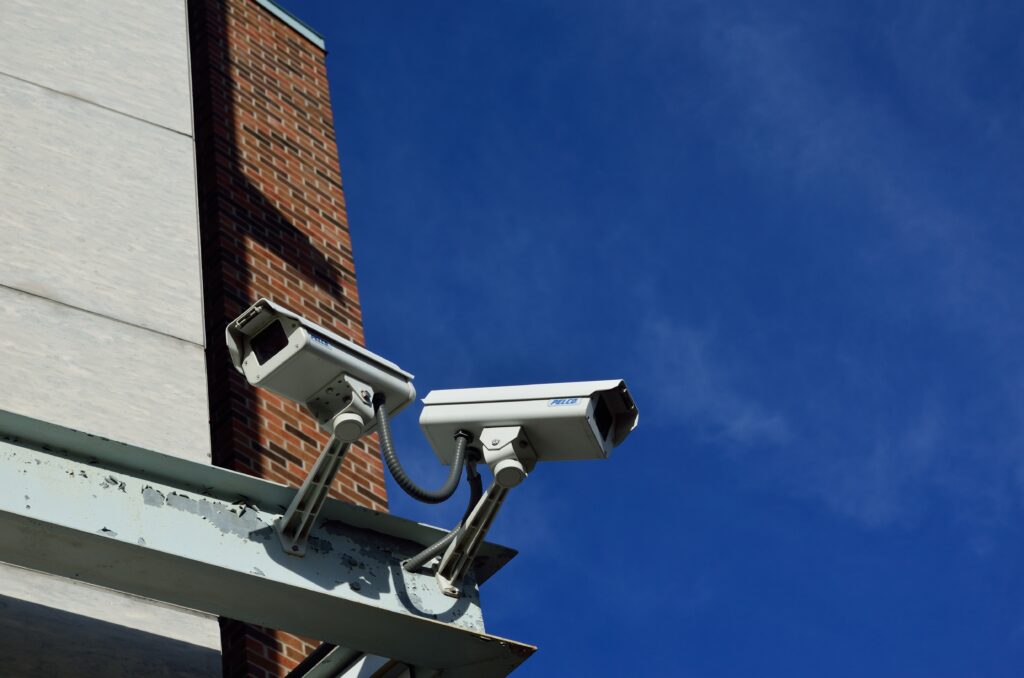 Twin surveillance cameras on a metal bar facing opposite directions